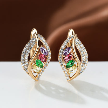 Gold earrings with colorful gemstones on a white surface with a brown background